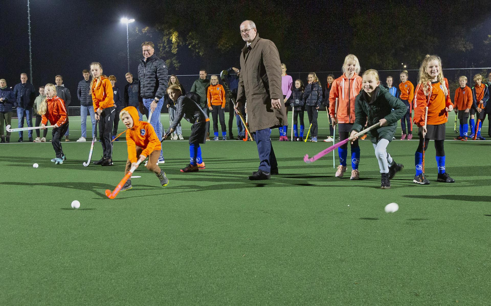 Burgemeester Loohuis bespeelt samen met kinderen van HHC het vernieuwde hockeyveld aan de Sportlaan.