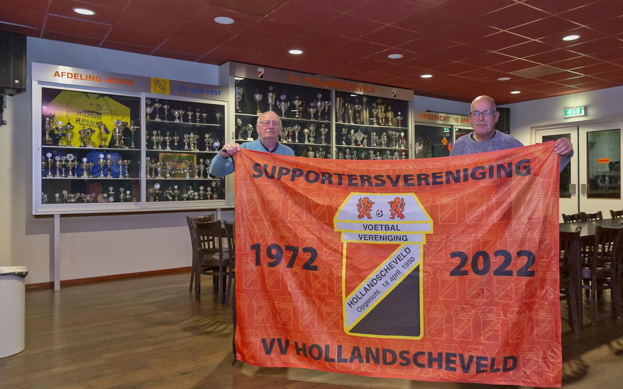 Oprichter Jan Kroezen (links) en voorzitter van de supportersvereniging van vv Hollandscheveld Arend Jan Vos, tonen de vlag, die het bestuur kreeg ter gelegenheid van het 50-jarig bestaan.