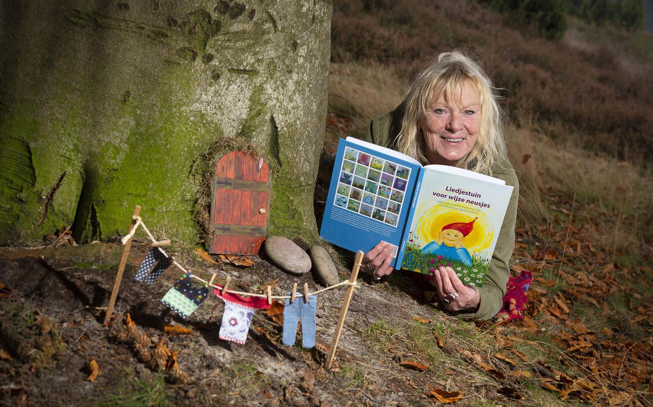 Herma Everts toont trots haar boek bij het door haar gemaakte kaboutertafereel in het bos. 