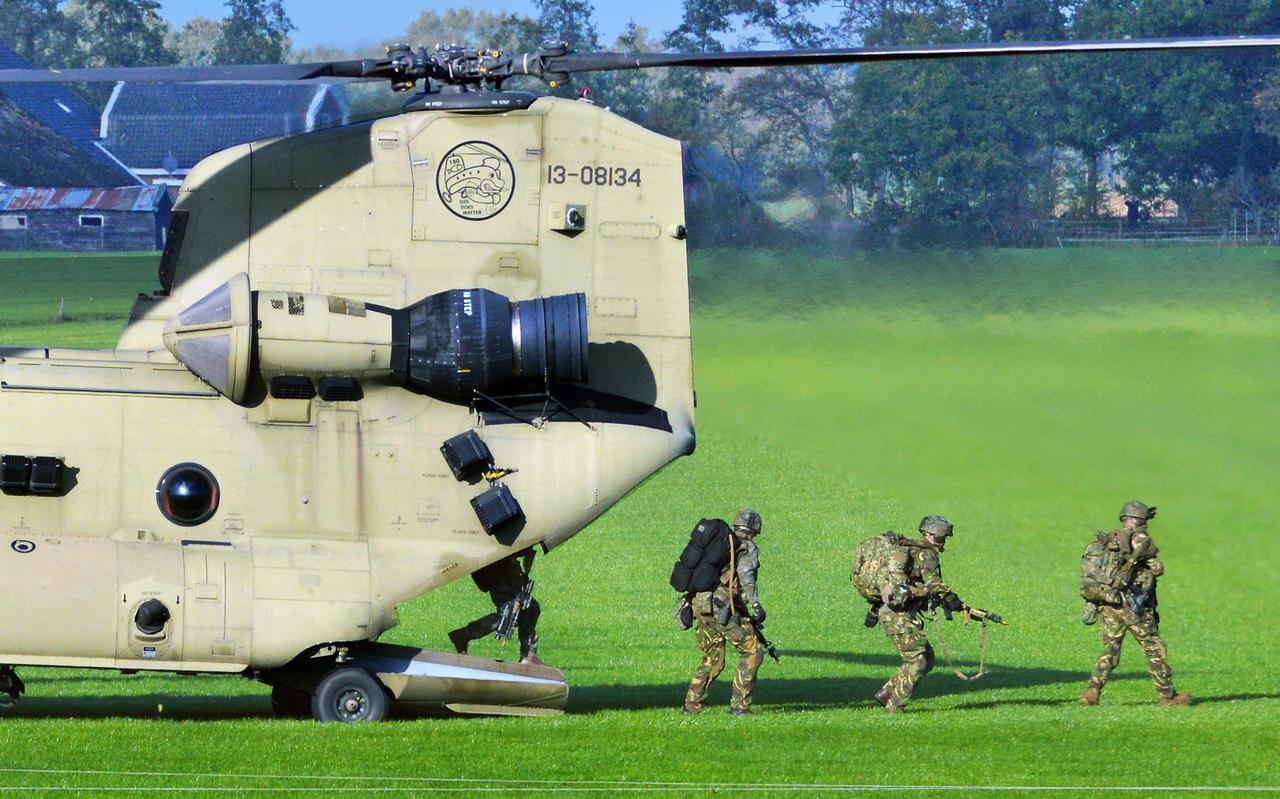 Zwaarbewapende militairen verlaten een Amerikaanse Chinook in een weiland vlakbij de Ossesluis bij De Wijk. 