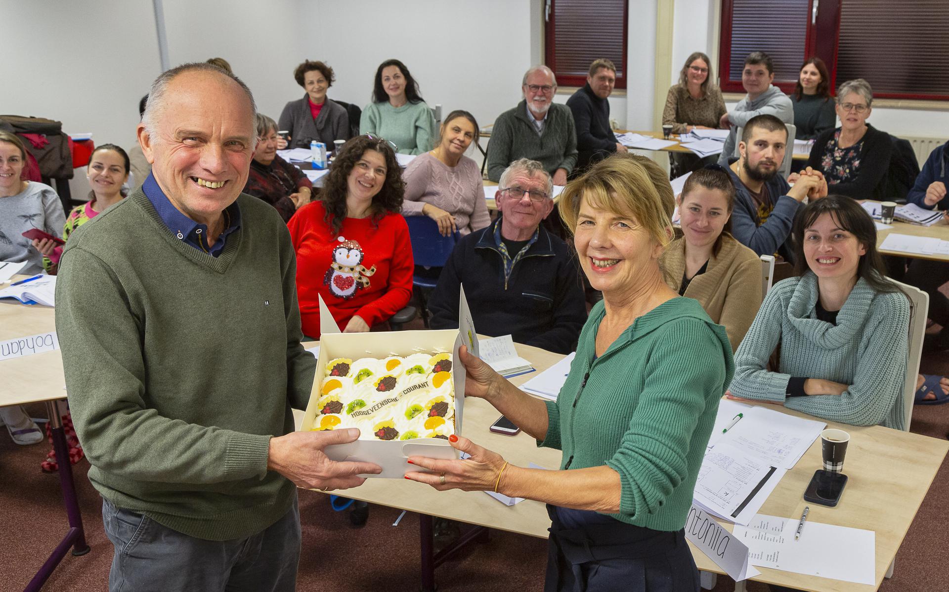 Henk van Dalsem reikt de taart van de week uit aan lerares Trudy Sturkenboom.