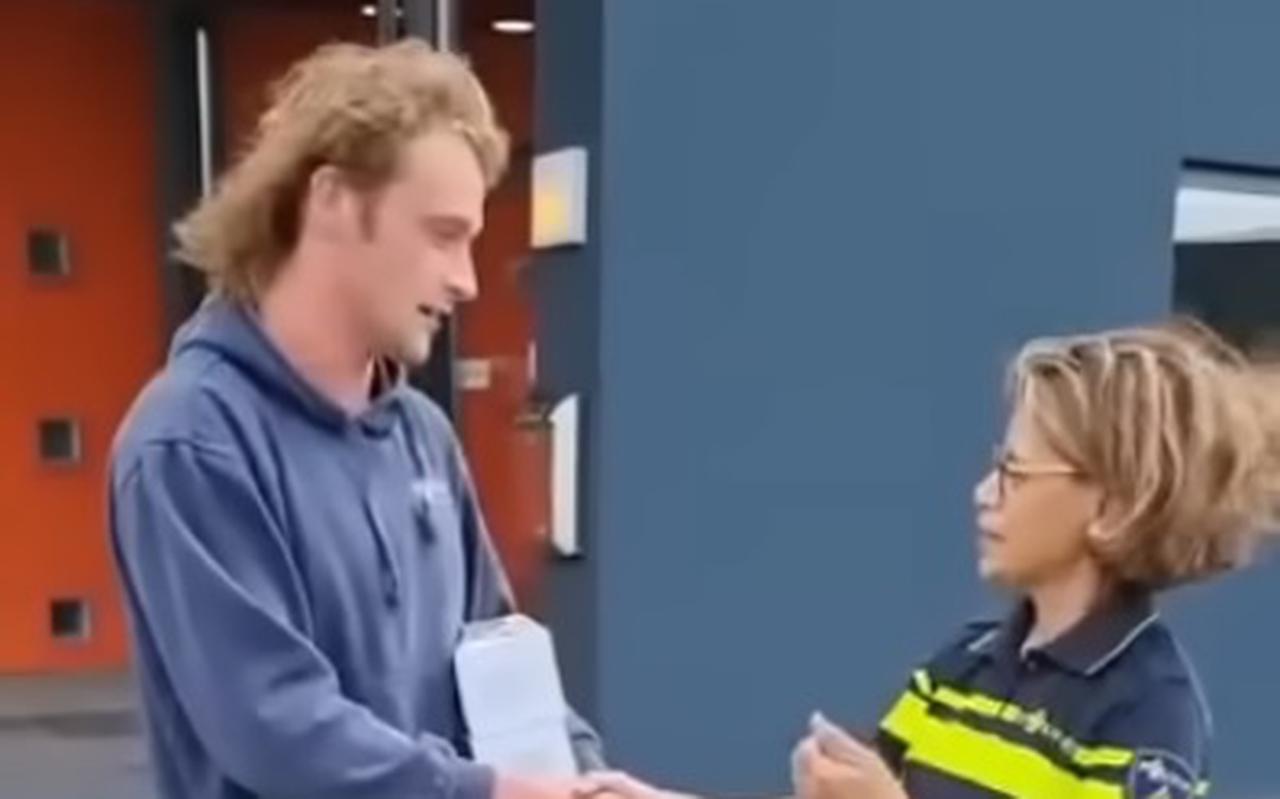 Tim overhandigt een politieagente in Groningen taart.